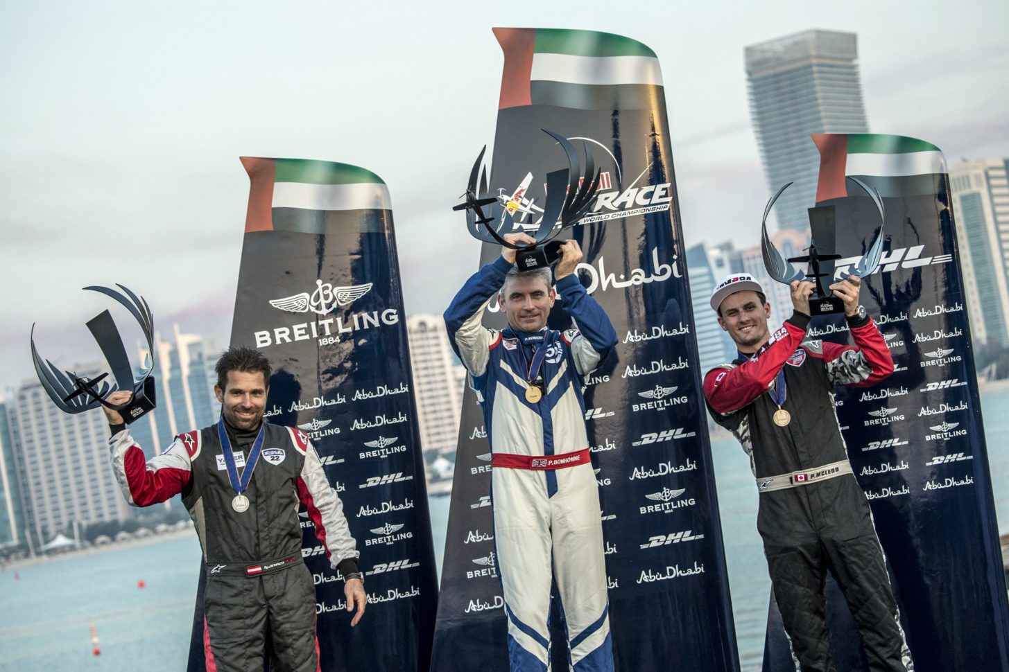 Hannes Archof/Österreich (links), Paul Bonhomme/Großbritannien (Mitte) und Pete McLeod/Kanada (rechts) feiern Ihren Sieg der ersten Etappe des Red Bull Air Race 2014 in Abu Dhabi