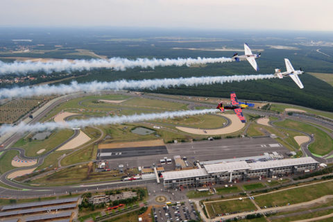 Kirby Chambliss (USA), Martin Sonka (Tschechien) und Matthias Dolderer (Deutschland) fliegen in Formation über den Kurs des Red Bull Air Race am EuroSpeedway Lausitz am 4. August 2010