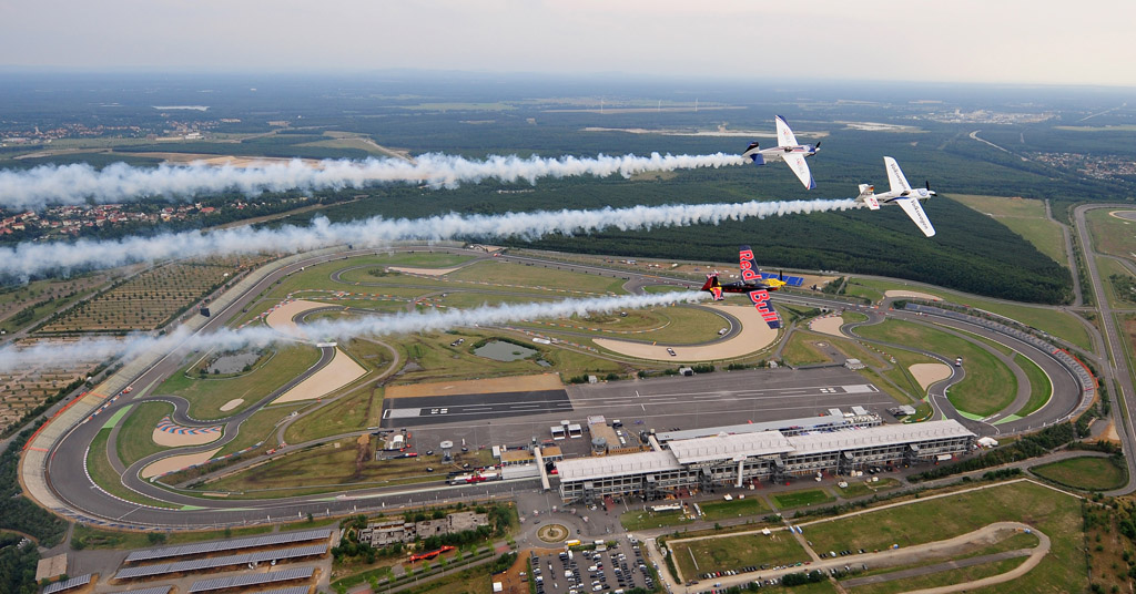 Kirby Chambliss (USA), Martin Sonka (Tschechien) und Matthias Dolderer (Deutschland) fliegen in Formation über den Kurs des Red Bull Air Race am EuroSpeedway Lausitz am 4. August 2010