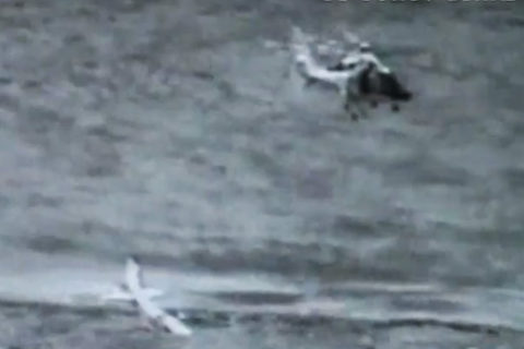 Der Pilot steht auf der Tragfläche und wartet auf die Bergung durch den Helikopter