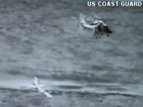 Der Pilot steht auf der Tragfläche und wartet auf die Bergung durch den Helikopter