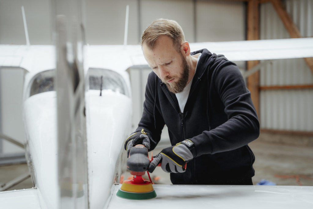 Mit einer Poliermaschine poliert Björn Tretow das Flugzeug.