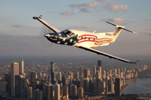 Eine PC-12 der Pilatus Aircraft in Sonderlackierung mit USA-Flagge fliegt über dem Lake Michigan bei Chicago.