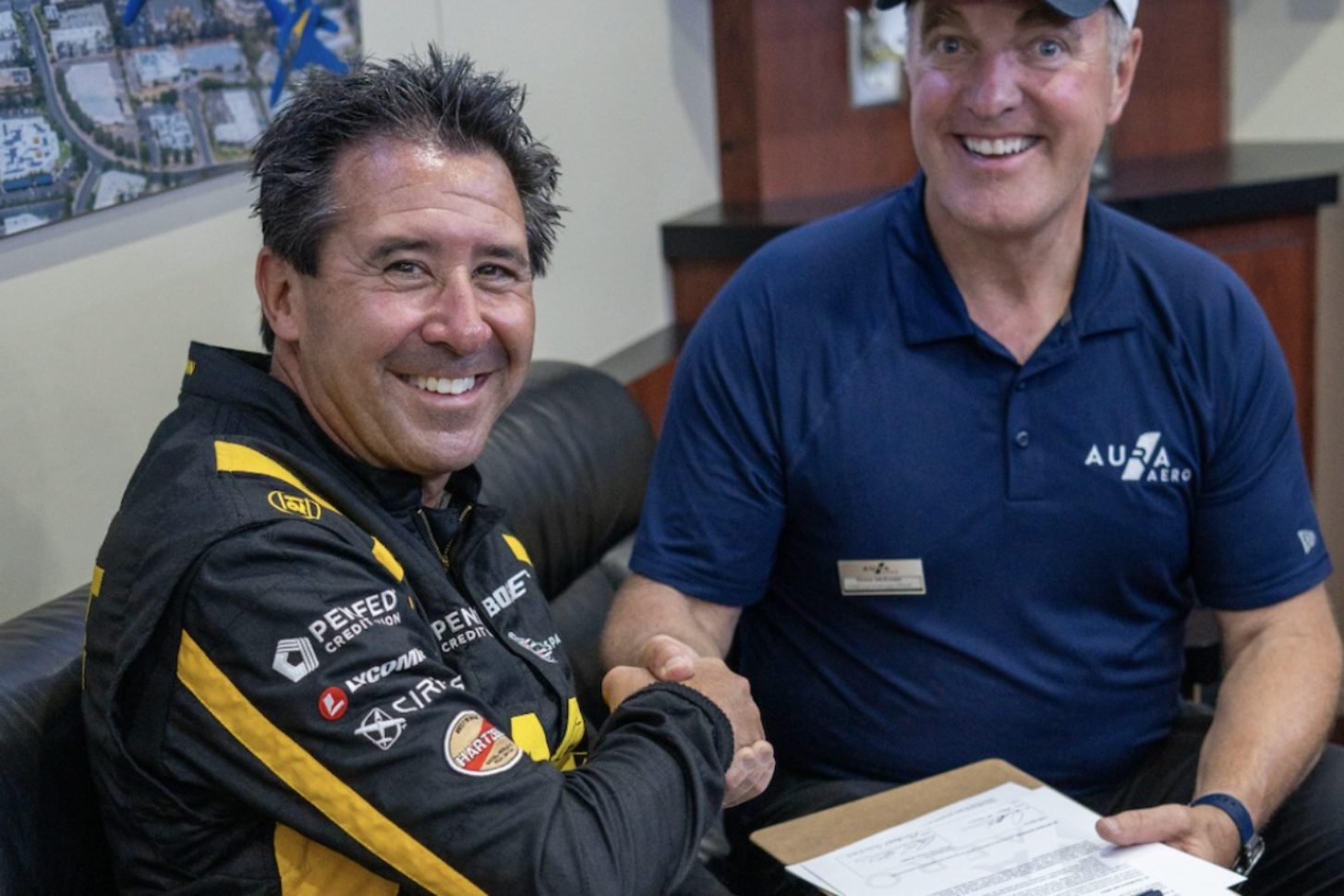 Mike Goulian und Drew McEwen, Chief Commercial Officer von AURA AERO, unterzeichnen die Vereinbarung auf der EAA AirVenture Oshkosh 2025.
